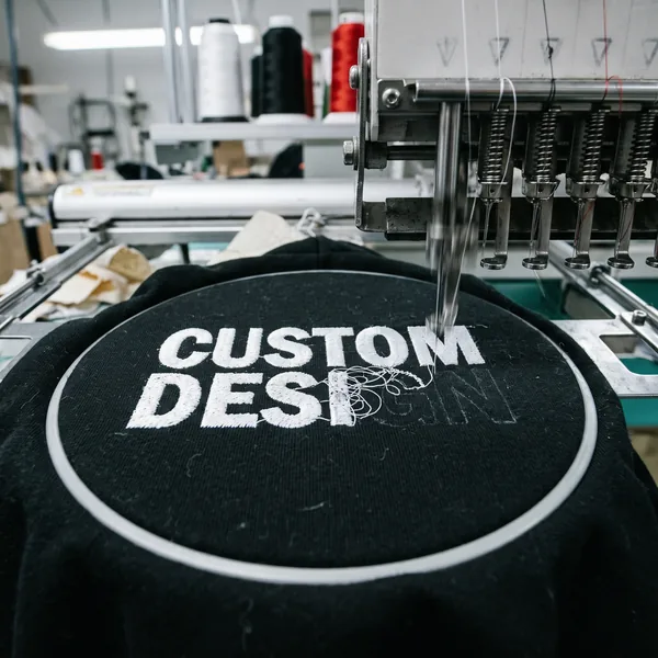 Embroidery machine stitching custom design lettering on a hoodie