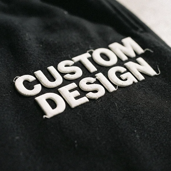 Raised puff print reading CUSTOM DESIGN on black sweat shorts