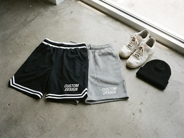 Streetwear mesh and fleece sweat shorts with CUSTOM DESIGN print on a concrete floor