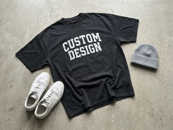 Oversized heavyweight T-shirt with a CUSTOM DESIGN screen print on a concrete floor next to sneakers