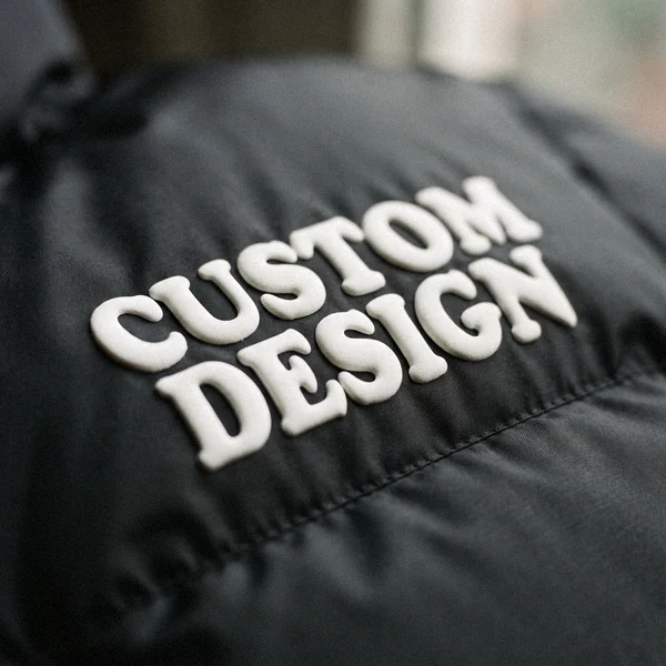 Raised puff print reading CUSTOM DESIGN on a black puffer jacket