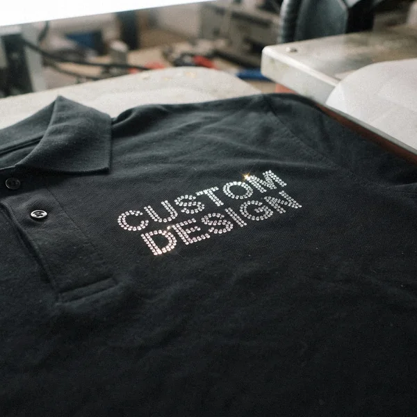 CUSTOM DESIGN lettering in heat-set rhinestones on a black polo shirt
